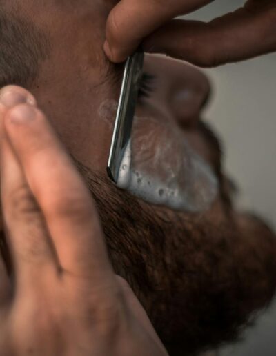 Detailed close-up image of a barber using a razor for precise beard trimming in the barbershop.