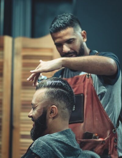 Skilled barber styling a man's hair in a modern barbershop setting, creating a trendy look.