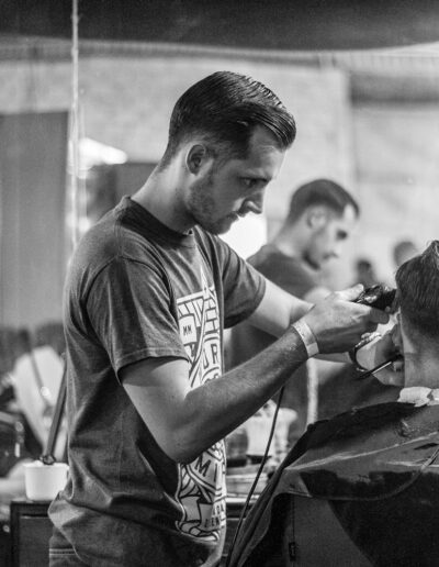 A barber skillfully gives a haircut in a stylish Wrocław barbershop, captured in moody monochrome.