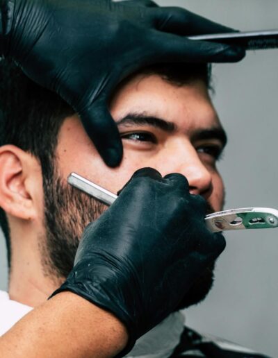 Close-up of a barber shaving a man's beard with precision in a contemporary barbershop setting.